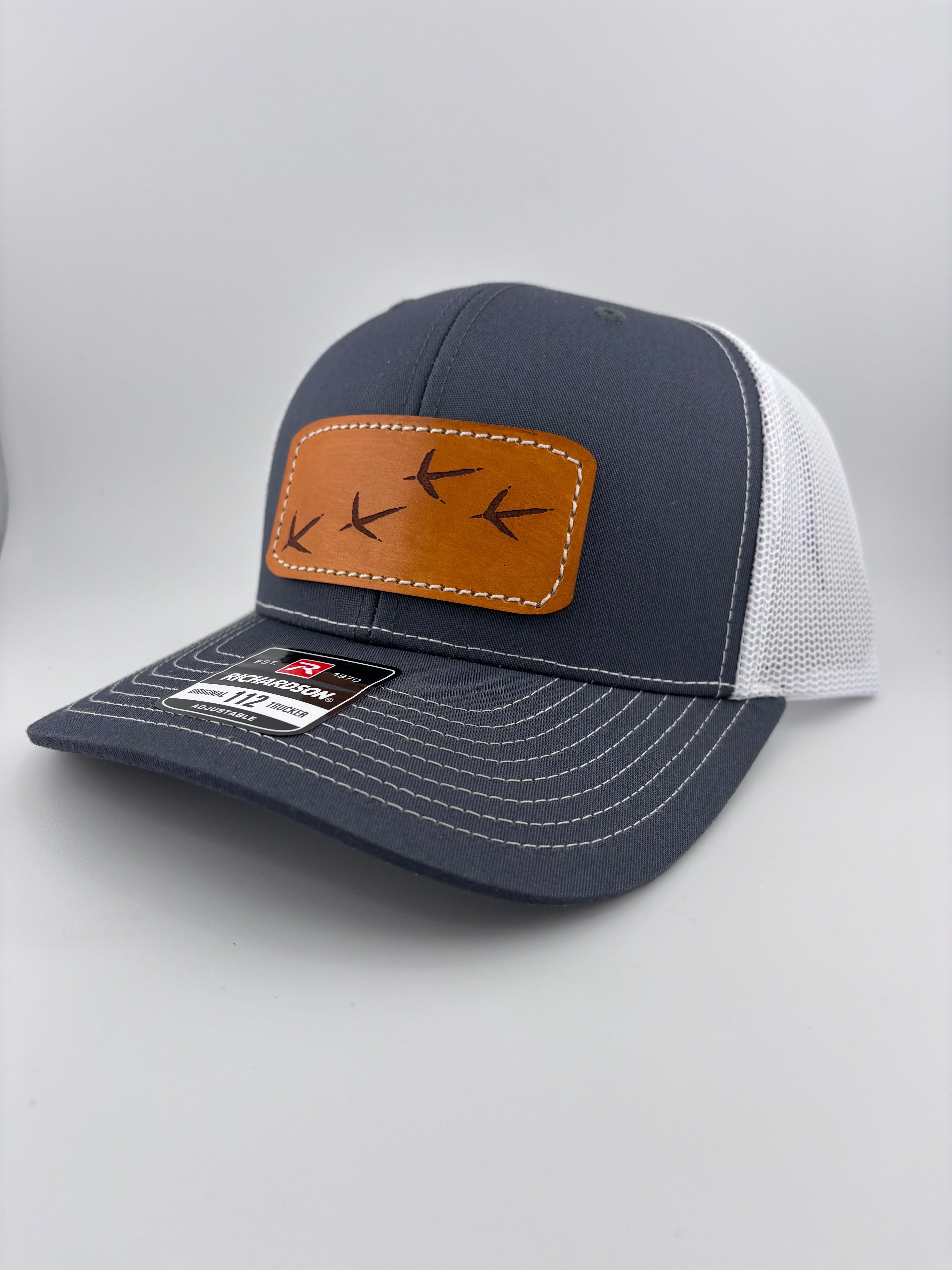 Gray cap with brown leather patch on a light gray background